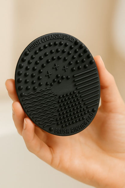 Black brush cleaning pad held in a hand against a neutral background